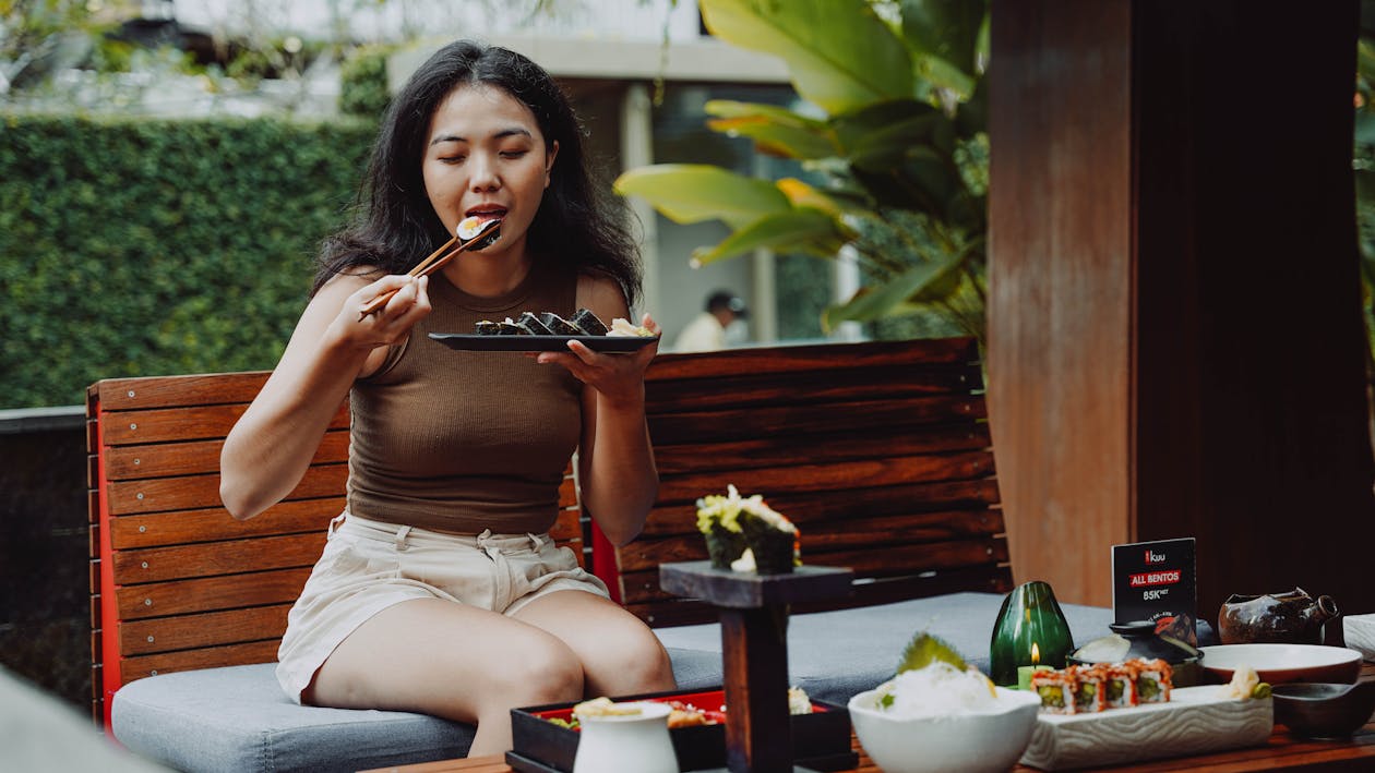 Woman sitting and eating sushi, representing binge eating behavior